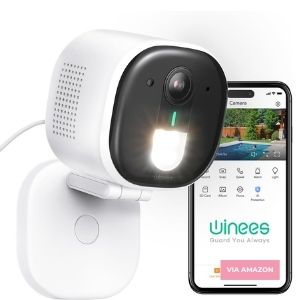 A white security camera with a built-in light is shown next to a smartphone displaying a camera feed and control app interface.